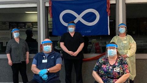 Staff stand in front of metis-nation flag