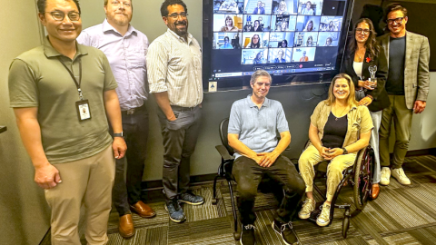 people standing around a screen with an award