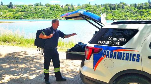 A community paramedic retrieves a medical bag from the back of a paramedic vehicle.
