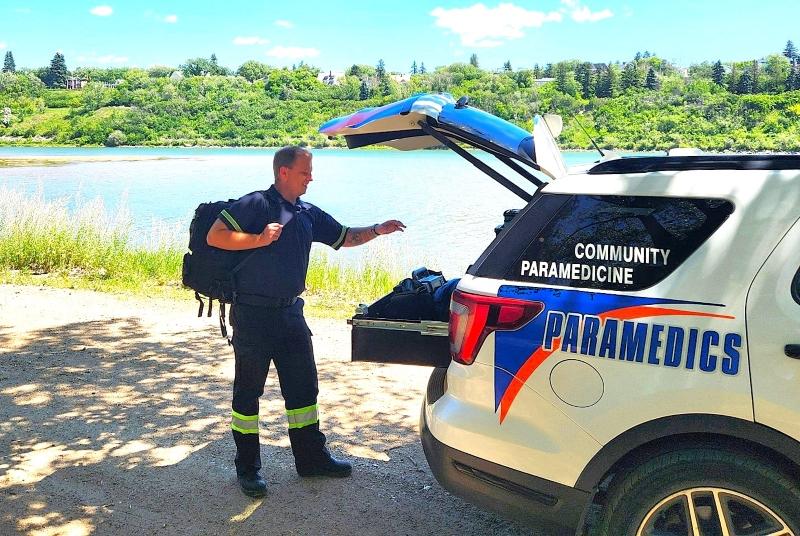 A community paramedic retrieves a medical bag from the back of a paramedic vehicle.